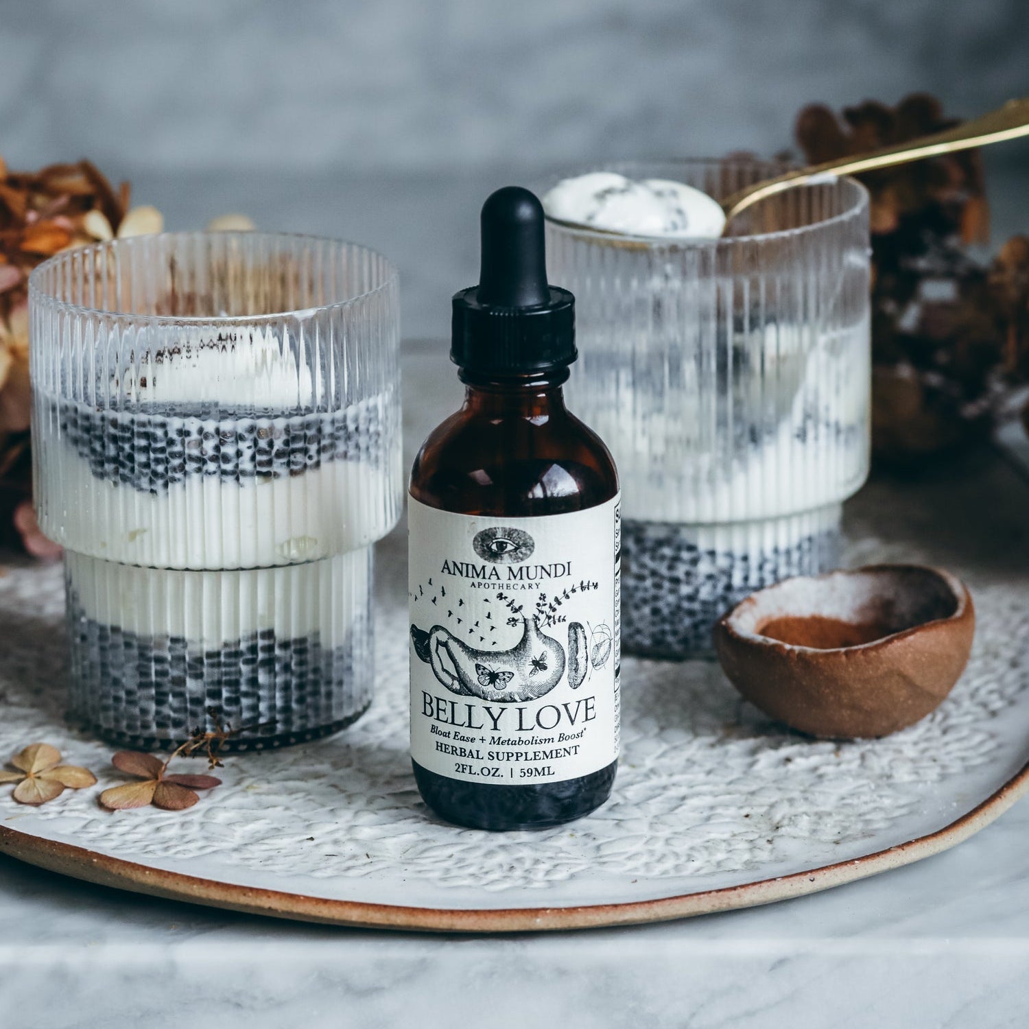 Bottle of 'Belly Love' supplement on a decorative tray with candles and wooden bowl.