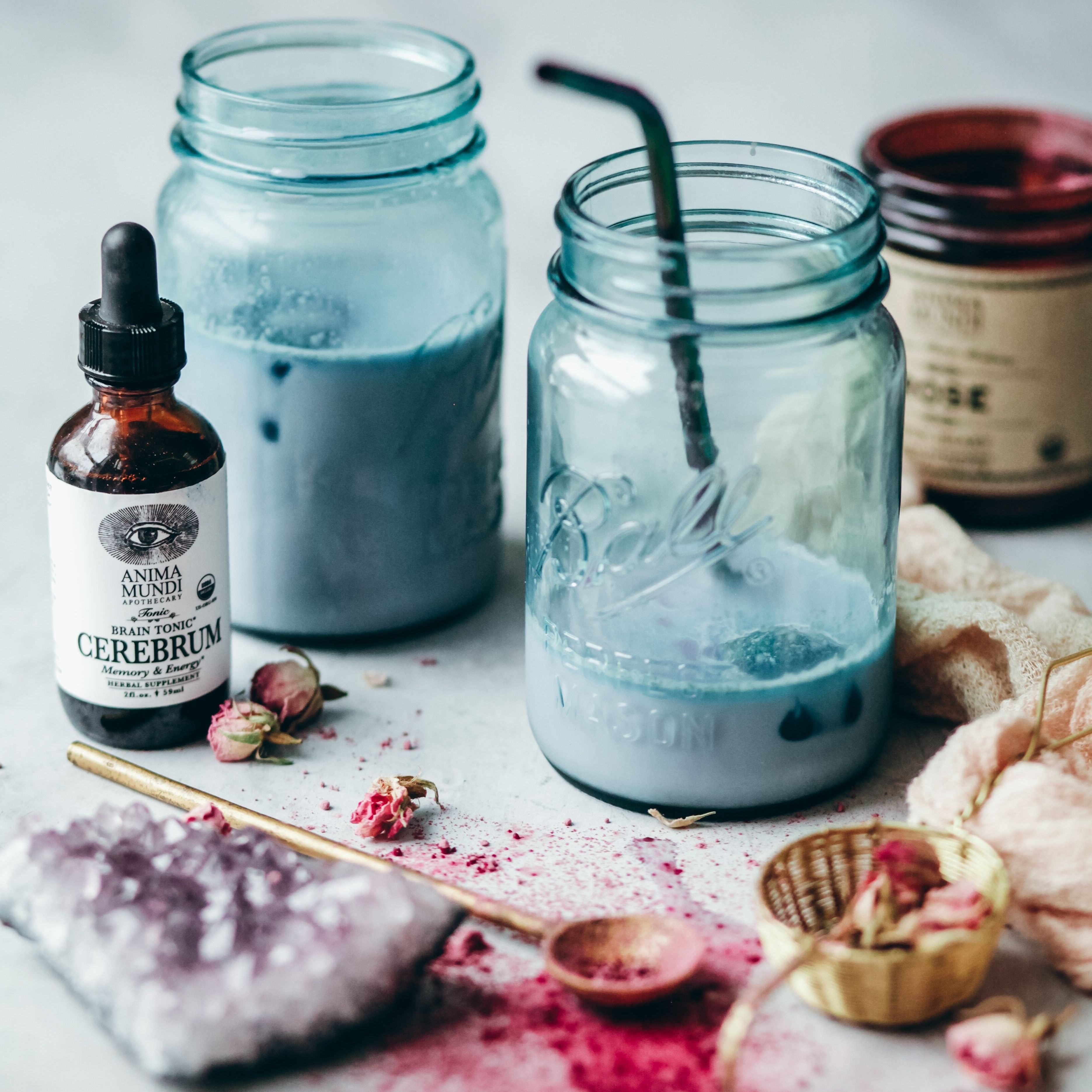 Blue liquid in jars with a bottle labeled 'Anima Mundi' on a light surface.