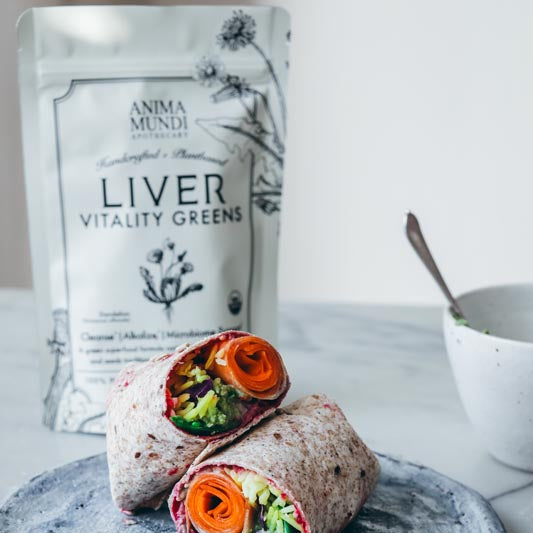 Colorful wrap with vegetables on a plate with 'Anima Mundi' liver vitality greens packaging in the background.