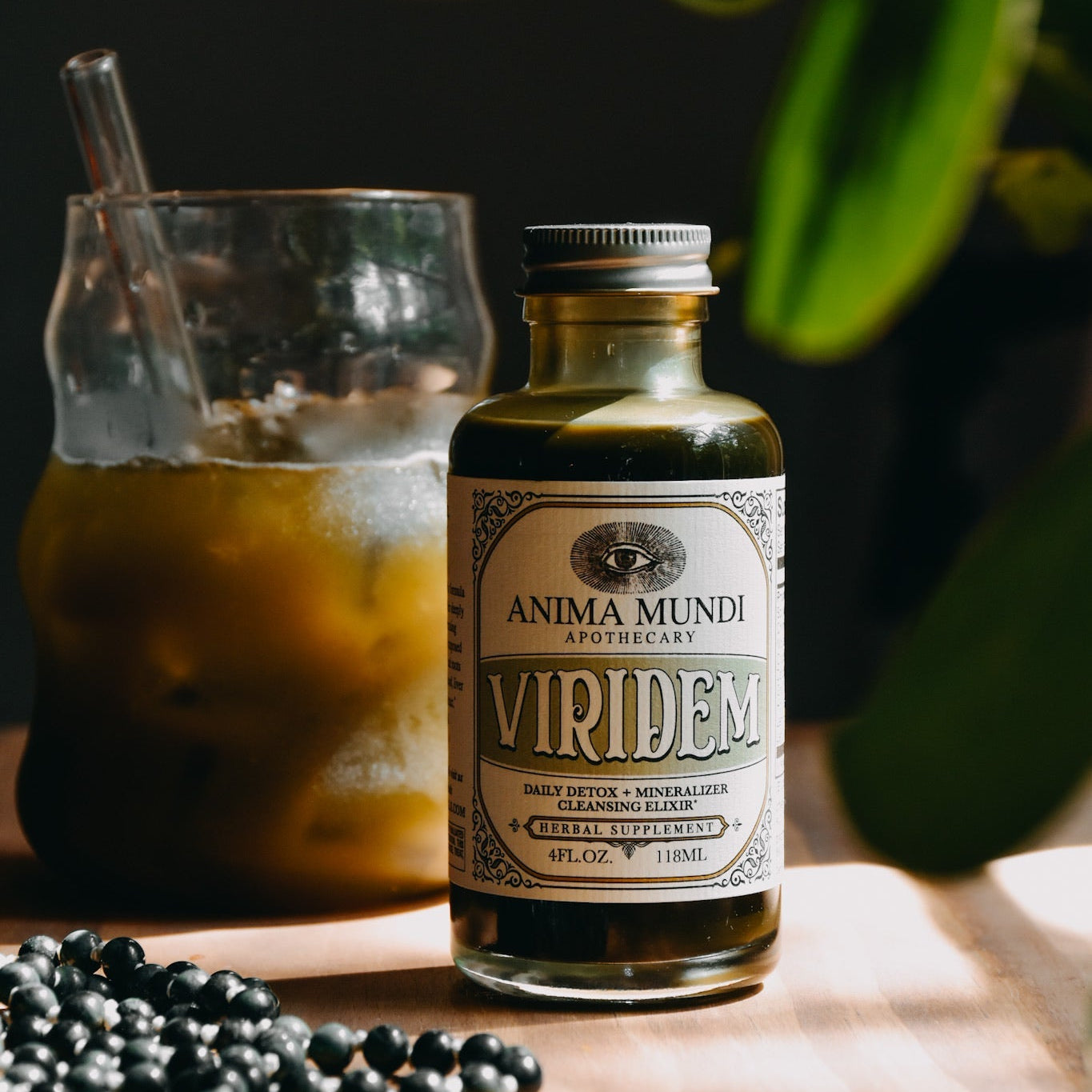Bottle of Anima Mundi Virides on a wooden surface with a glass and berries in the background.