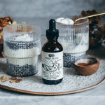 Bottle of 'Belly Love' supplement on a decorative tray with candles and wooden bowl.