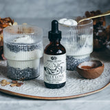 Bottle of 'Belly Love' supplement on a decorative tray with candles and wooden bowl.