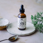 Bottle of Anima Mundi Cerebrum on a white plate with a spoon and plant in the background.
