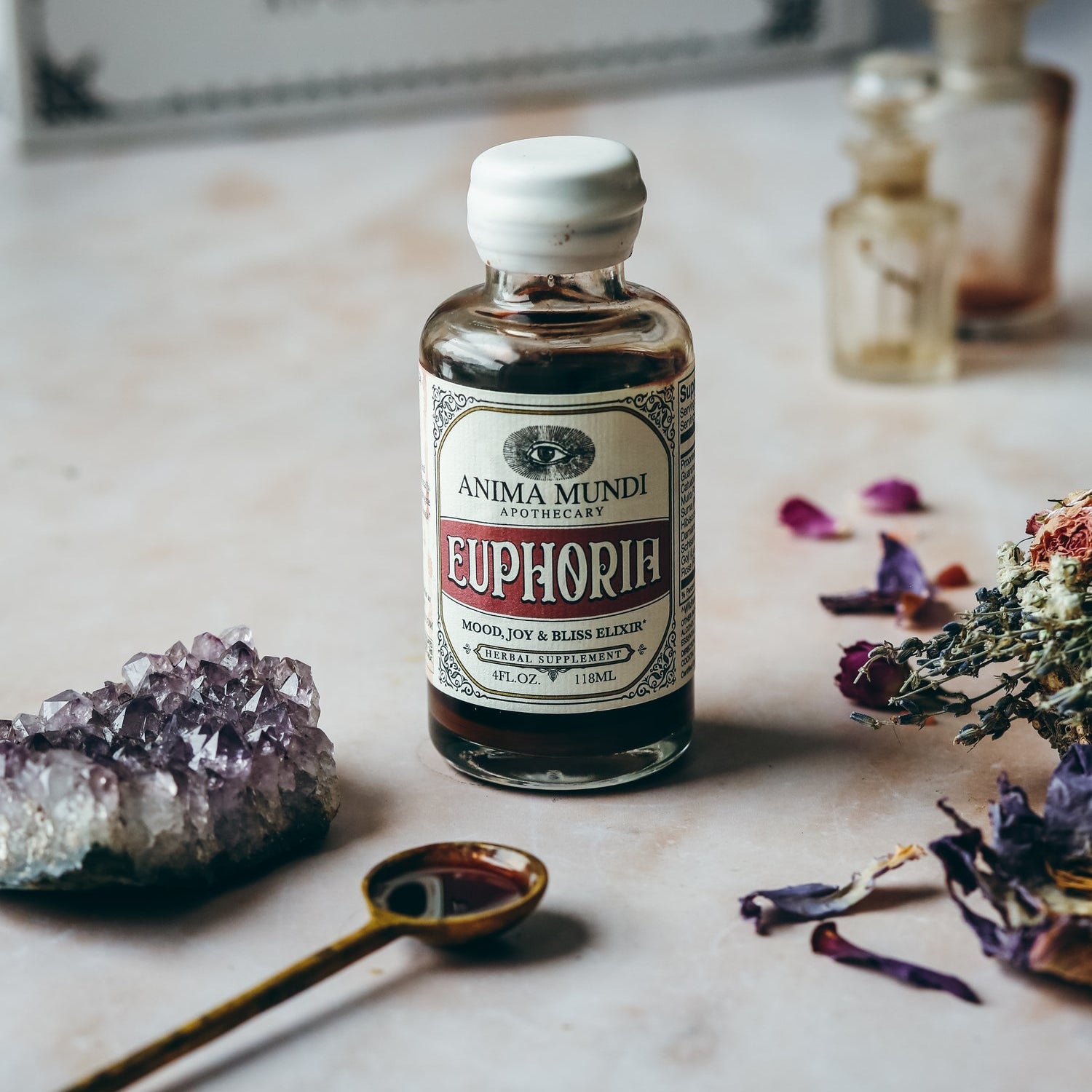 Bottle of Anima Mundi Euphoria on a marble surface with crystals and flowers.