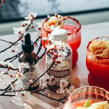 HAPPINESS Tonic and EUPHORIA on a table with floral decorations and vibrant drinks.