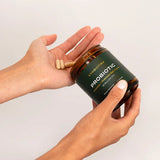 Person holding Cymbiotika Probiotic jar with capsules in hand, emphasizing daily gut health supplement.