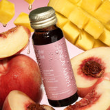 Glow Shots Marine Collagen dietary supplement bottle surrounded by fresh apples and mango slices.