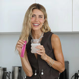 Happy woman holding a sachet and drink made with Happiest Gut electrolytes, Lemon Ginger flavor.