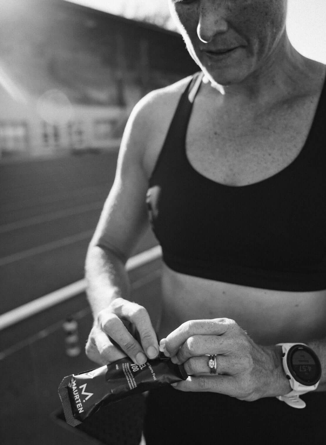 Athlete opening MAURTEN - Gel 100 sachet for energy during training.