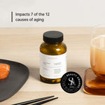 NOVOS Boost (NMN) supplement bottle on table with food and drink, impacts 7 of 12 causes of aging.