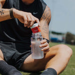 Athlete adding Everyday Hydration Salts Raspberry to a water bottle for effective hydration.